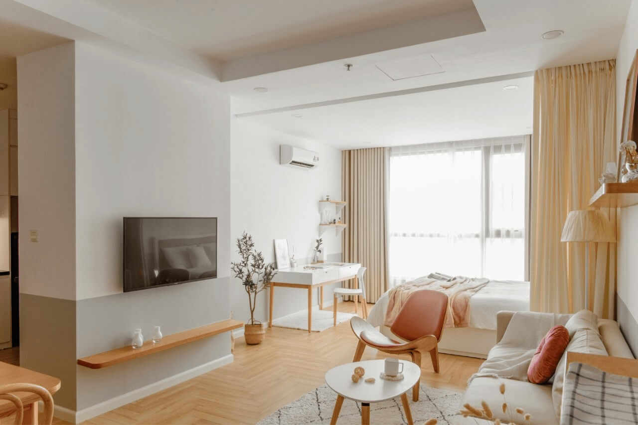 Phòng khách nhỏ gọn, nội thất hiện đại, gam màu sáng với sofa, bàn trà và ti vi treo tường.