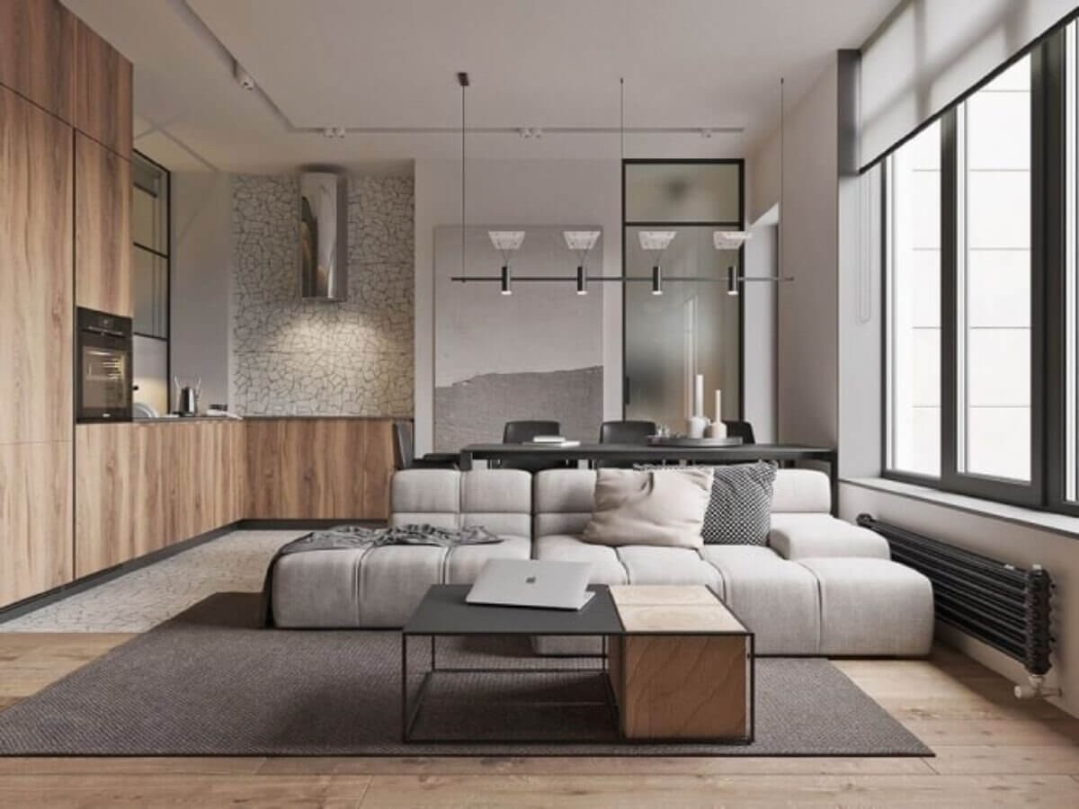 Phòng khách hiện đại với sofa xám, bếp mở và ánh sáng tự nhiên từ cửa sổ lớn.