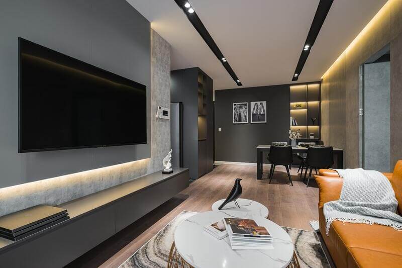 Phòng khách hiện đại với ghế sofa da cam, bàn trà trắng, tivi lớn và nội thất tối giản.