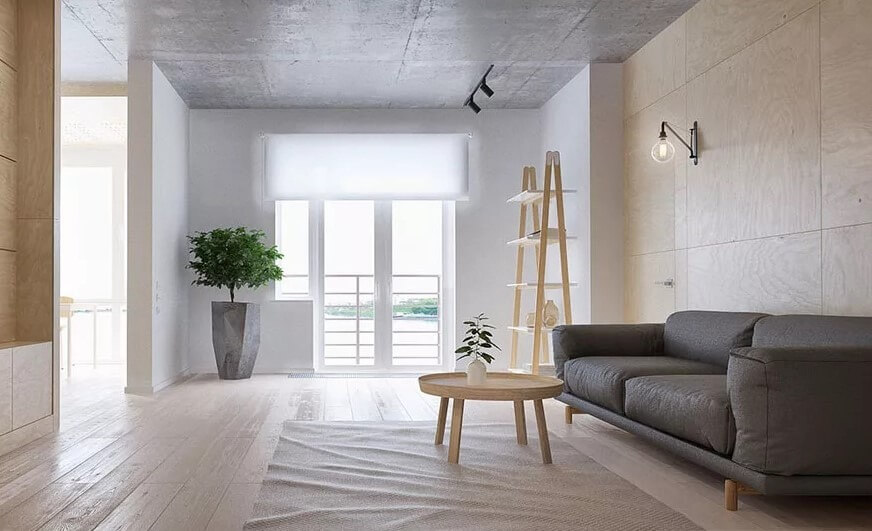 Phòng khách tối giản với ghế sofa xám, cây xanh và bàn gỗ bên cửa sổ sáng.