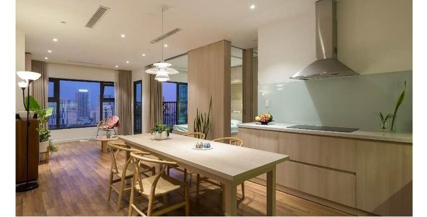 Phòng bếp hiện đại với bàn ăn gỗ và cửa sổ nhìn ra thành phố, trang trí đèn treo và cây xanh.