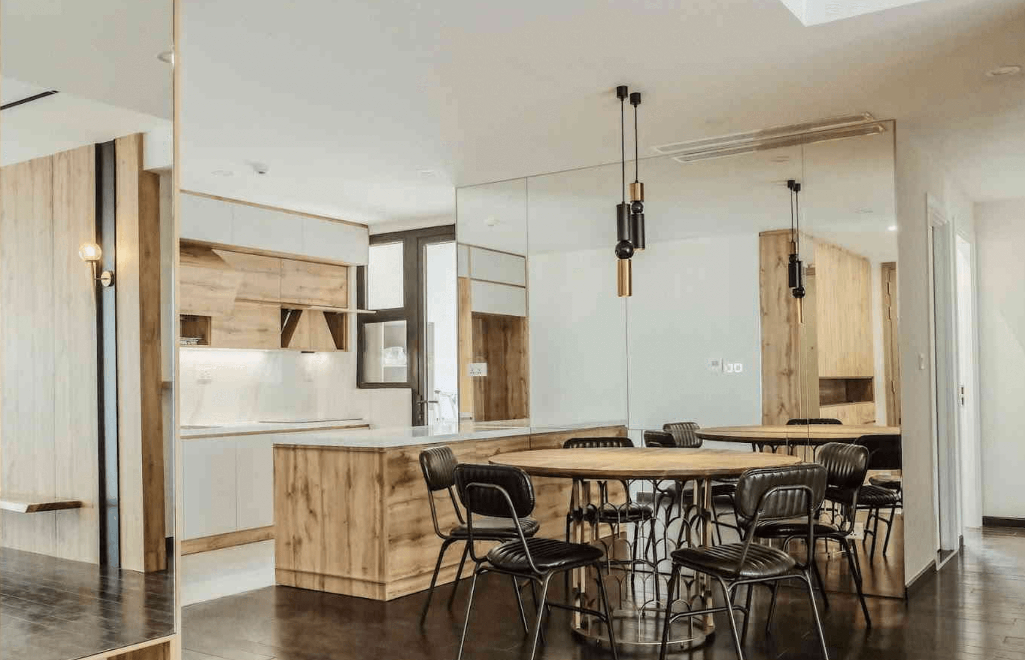 Phòng bếp hiện đại với nội thất gỗ, bàn ghế phong cách công nghiệp, đèn trần trang trí.