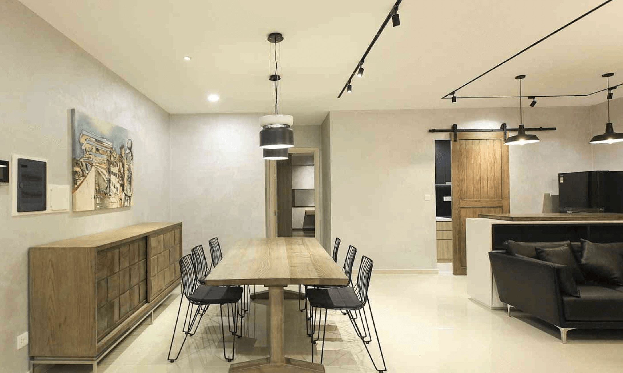 Phòng ăn hiện đại với bàn gỗ dài, ghế đen và đèn treo phong cách công nghiệp trong không gian tối giản.