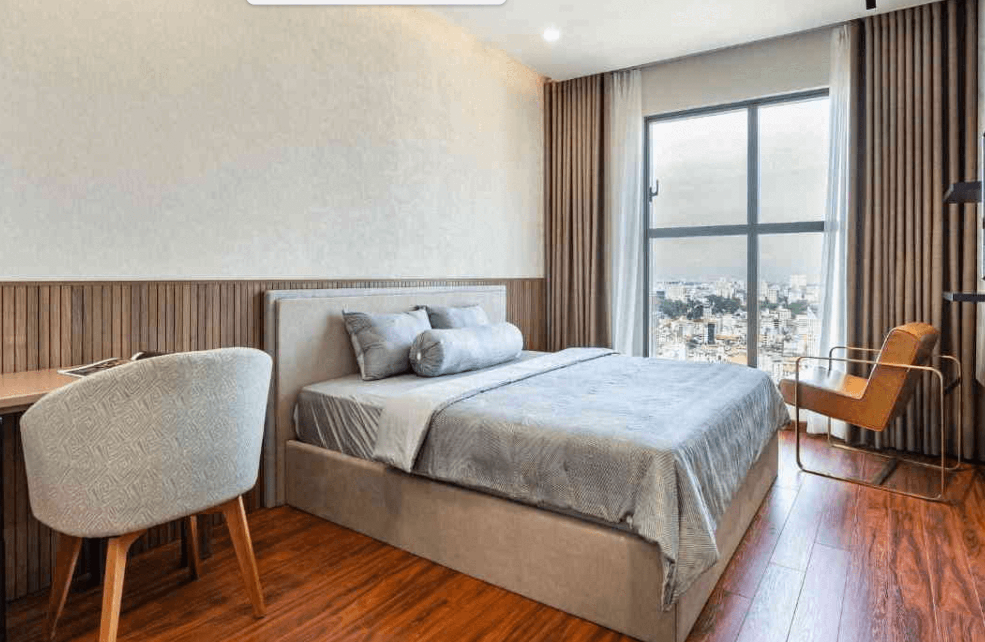 Phòng ngủ thoáng đãng, nội thất hiện đại với giường lớn và cửa sổ kính nhìn ra cảnh thành phố.