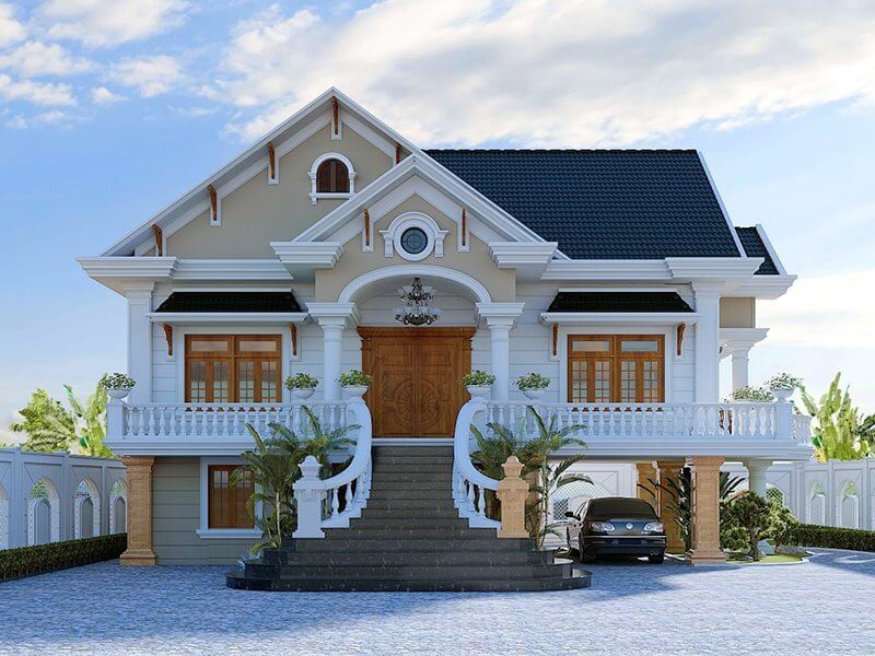 Nhà biệt thự hai tầng tân cổ điển với mái ngói xanh đậm và lối vào bậc thang, cây xanh bao quanh.