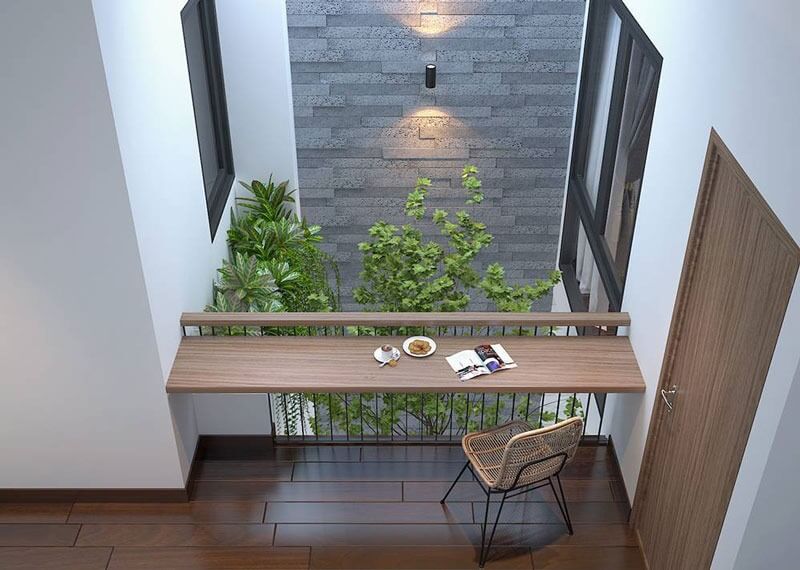 Không gian làm việc nhỏ với bàn gỗ, ghế mây và cây xanh trong nhà, thiết kế hiện đại, thoáng đãng.