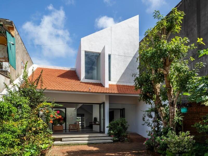 Ngôi nhà mái ngói đỏ hiện đại với nhiều cây xanh xung quanh; không gian sống thoáng mát và sáng sủa.