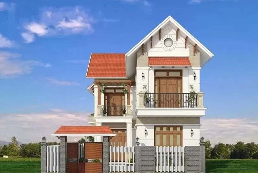 Ngôi nhà hai tầng mái ngói đỏ, ban công rộng và cửa gỗ, nằm giữa cánh đồng xanh, bầu trời trong xanh.