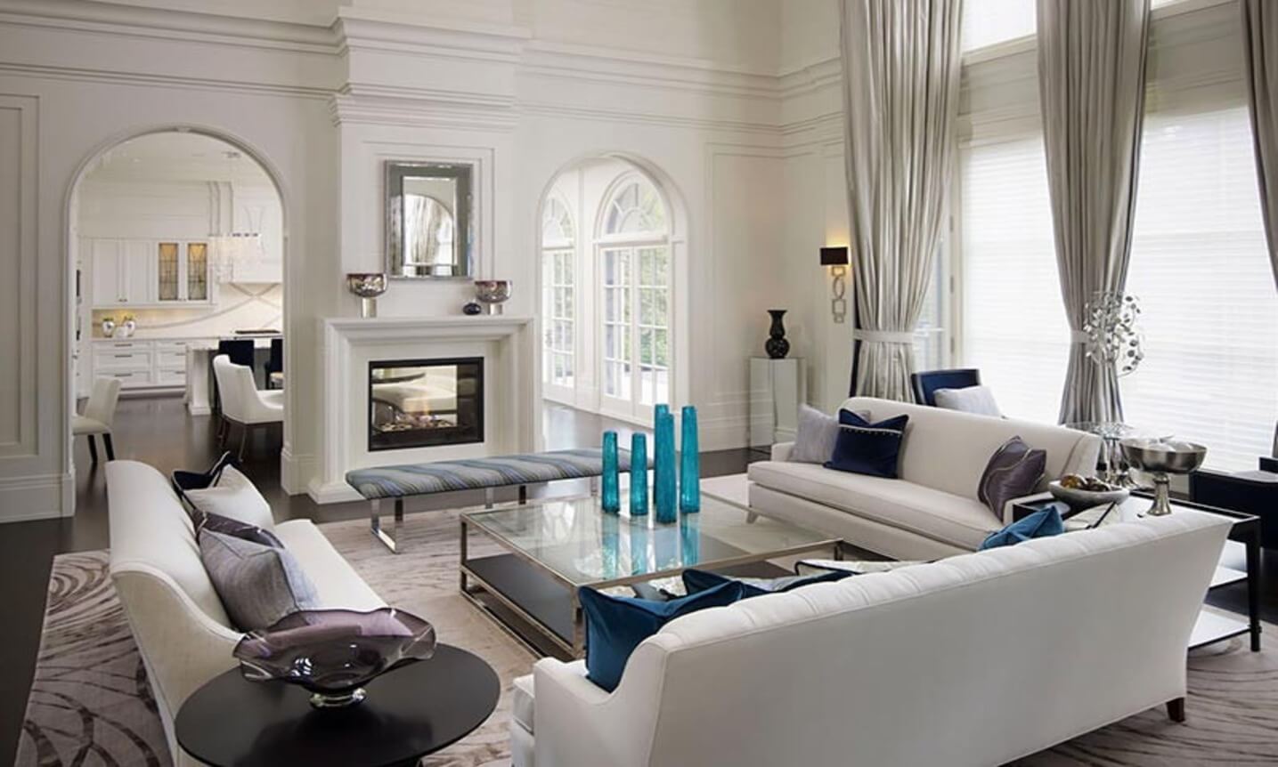 Phòng khách sang trọng với nội thất màu trắng và kính trang trí, ánh sáng tự nhiên từ cửa sổ lớn.