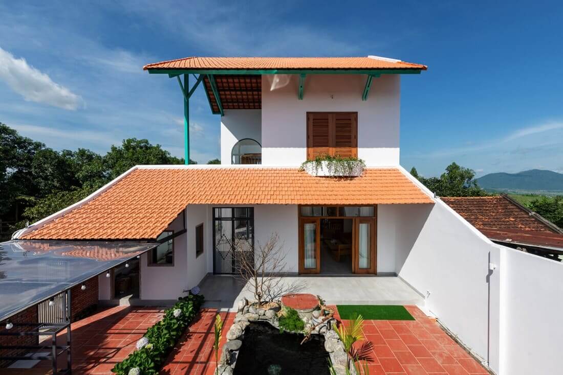 Ngôi nhà mái ngói đỏ, kiến trúc hiện đại, sân vườn nhỏ, bầu trời xanh.