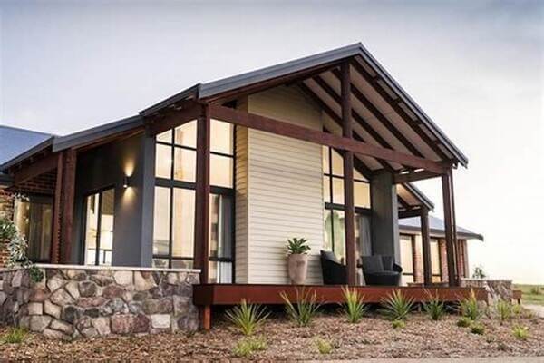 Ngôi nhà hiện đại với mái hiên rộng, cửa kính lớn và tường ốp đá, kết hợp kiến trúc truyền thống và hiện đại.