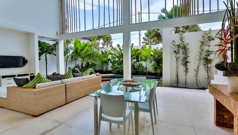 Không gian nội thất mở với bàn kính và ghế, cây xanh tạo cảm giác thư giãn trong nhà.