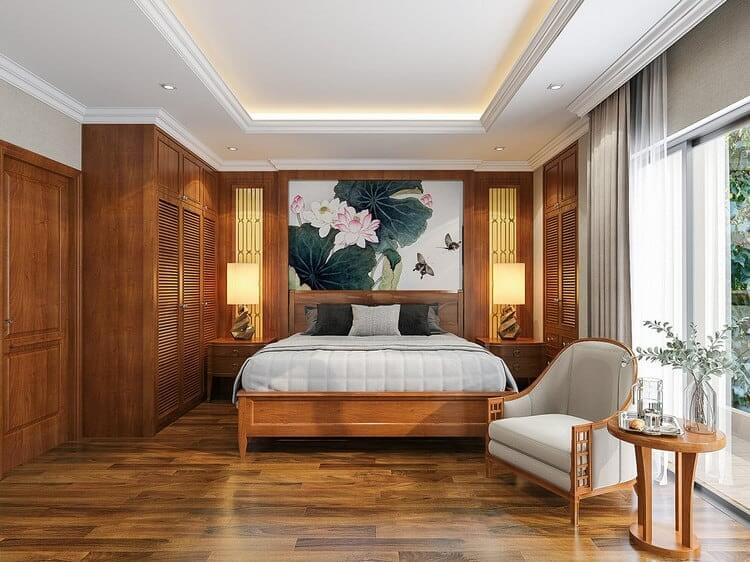 Phòng ngủ sang trọng với giường lớn, tranh hoa sen, đồ gỗ tự nhiên và ánh sáng ấm áp từ đèn bàn bên cạnh.