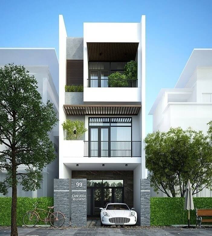 Nhà hiện đại ba tầng với xe hơi và xe đạp đỗ phía trước, có ban công và cây xanh.