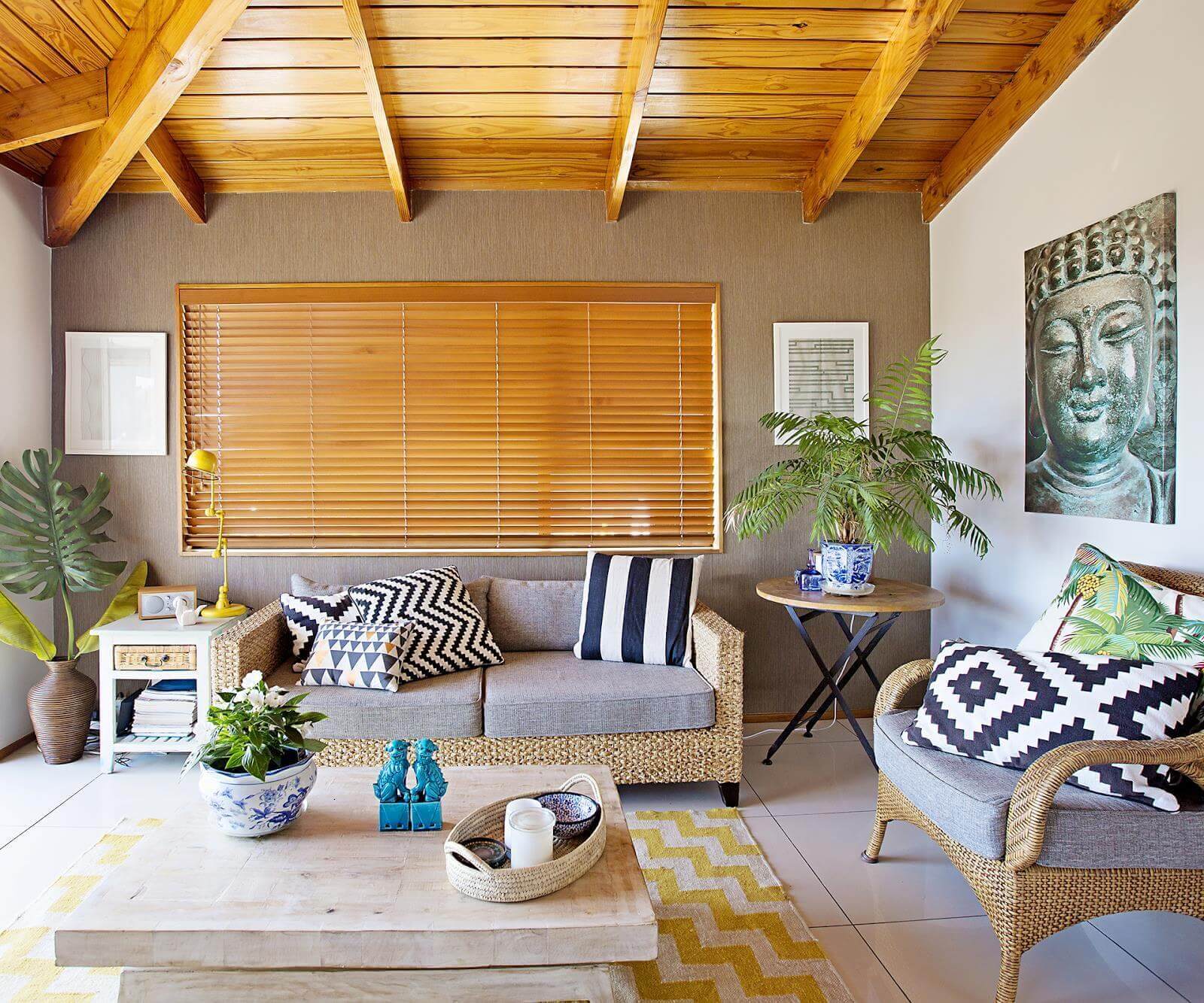 Phòng khách thoáng đãng với nội thất gỗ, sofa đan lát, tranh Phật và cây cảnh tạo không gian ấm cúng.