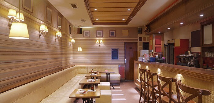 Quán cà phê phong cách hiện đại, ánh đèn ấm áp, bàn ghế gỗ. Không gian ấm cúng, lý tưởng cho gặp gỡ bạn bè.
