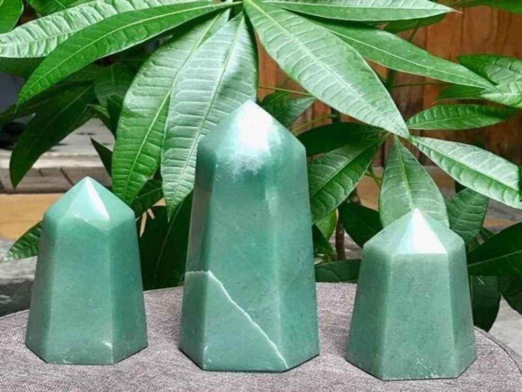 Ba cột đá thạch anh màu xanh lục trước nền cây xanh, tạo phong thủy tốt.