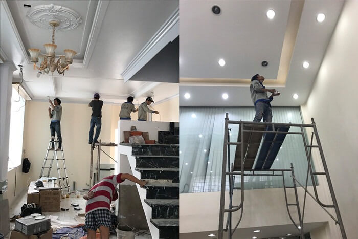 Công nhân thi công trần nhà và hệ thống đèn trong một công trình xây dựng nội thất.