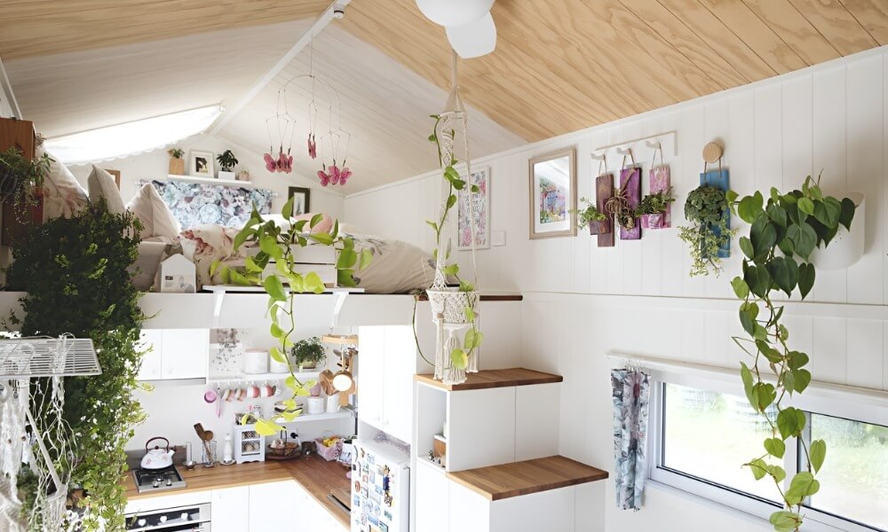 Căn nhà nhỏ gác xép ấm cúng với cây xanh và nội thất trắng sáng.