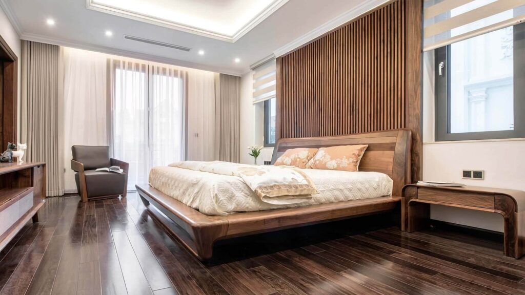 Phòng ngủ hiện đại với giường gỗ, ánh sáng tự nhiên và ghế bành êm ái.