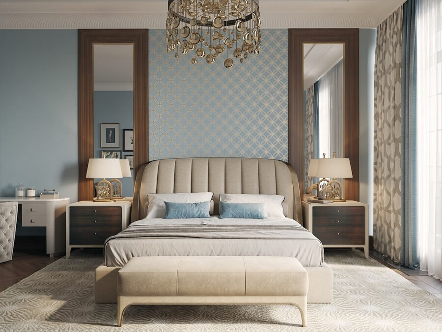 Phòng ngủ sang trọng với đèn chùm pha lê, giường lớn, hai bàn đầu giường, và giấy dán tường hoa văn xanh.