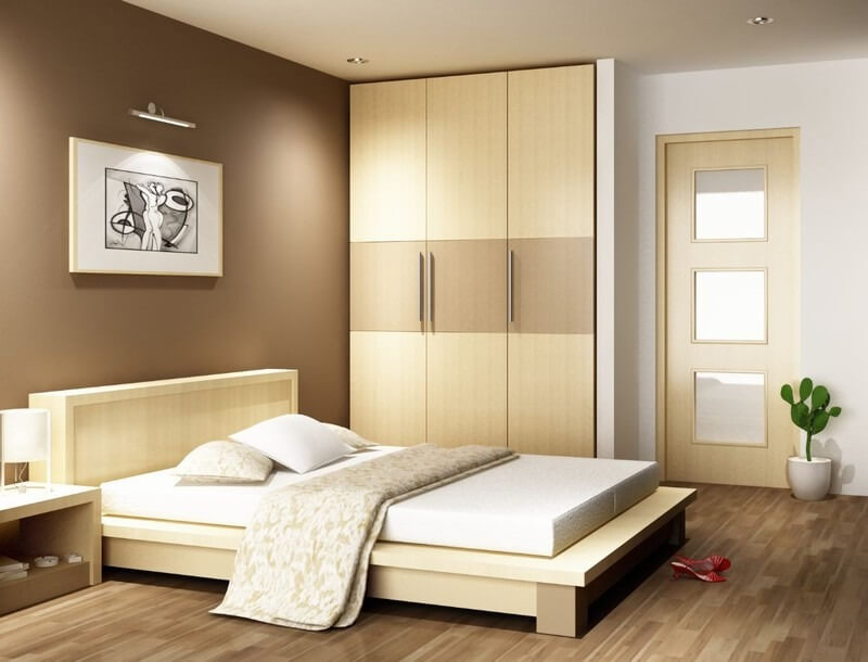 Phòng ngủ hiện đại với nội thất gỗ sáng màu, giường thấp, tranh treo tường và tủ quần áo lớn.