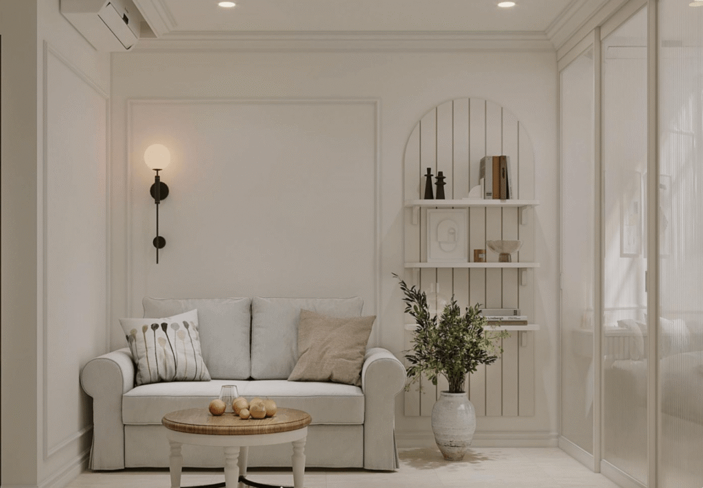 Phòng khách hiện đại với ghế sofa trắng, bàn tròn nhỏ, kệ tường và cây xanh tạo không gian thoải mái.