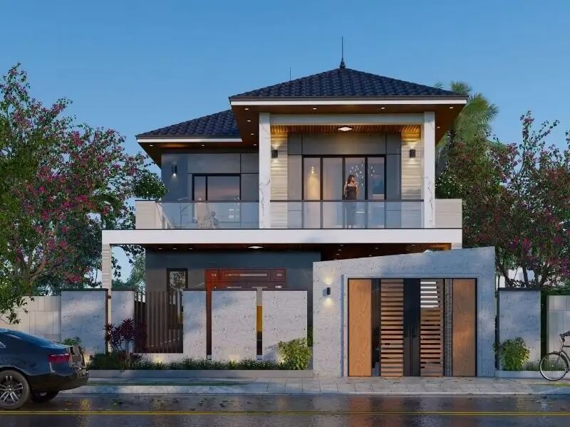 Ngôi nhà hiện đại hai tầng với cổng đá, mái ngói, cửa kính lớn, và cây xanh xung quanh.