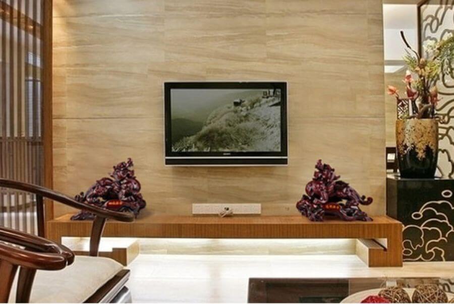 Phòng khách sang trọng với TV treo tường, tượng trang trí và bàn gỗ tinh tế.