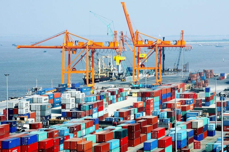 Bến cảng container với cần cẩu vận chuyển và biển xa, logistics và vận tải hàng hải.