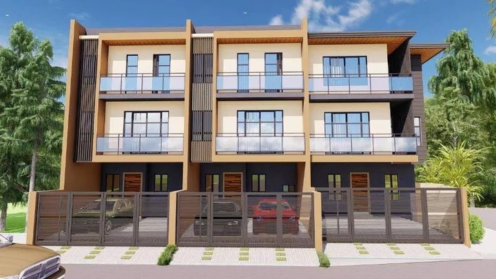 Dãy nhà phố hiện đại ba tầng với ban công kính và gara, trước cổng có hàng rào kim loại, trời quang đãng.