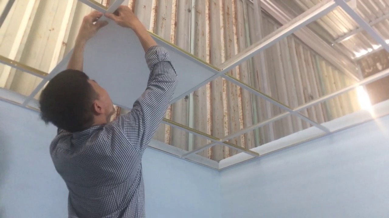 Người đàn ông đang lắp đặt trần la phông thạch cao trong phòng.