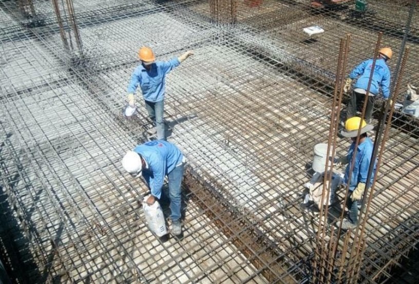 Công nhân đang làm việc trên công trường xây dựng với lưới thép cốt thép.