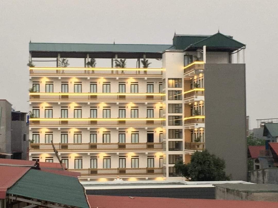 Tòa nhà cao tầng với đèn chiếu sáng ban đêm, mái xanh, nhìn từ bên ngoài trong khung cảnh thành phố buổi tối.