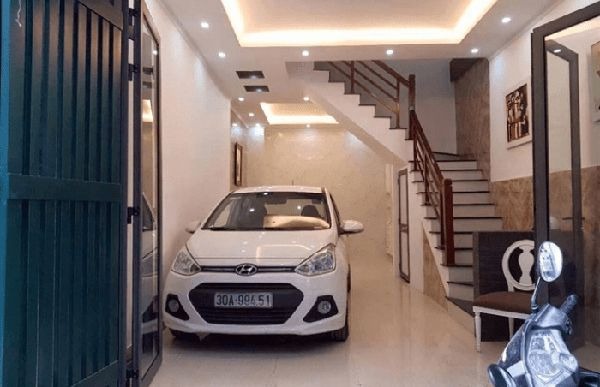 Ô tô trắng đậu trong gara nhà, bên cạnh là cầu thang dẫn lên tầng trên.