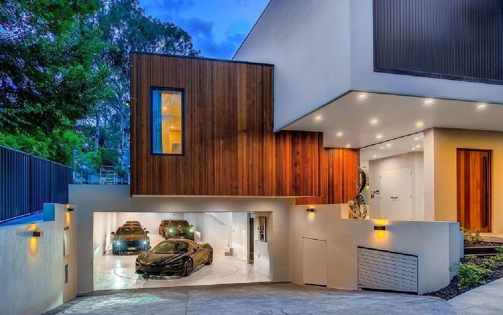 Nhà hiện đại với gara ô tô sang trọng, ánh sáng ban đêm, thiết kế gỗ và kính, không gian sống đẳng cấp.