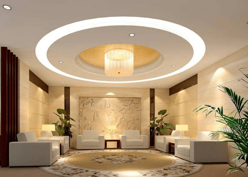 Phòng khách sang trọng với đèn trần hiện đại, ghế sofa trắng và cây cảnh trang trí.