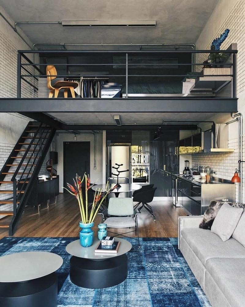 Căn hộ studio hiện đại với nội thất tối giản và gác lửng, trang trí bàn sofa và thảm xanh nổi bật.