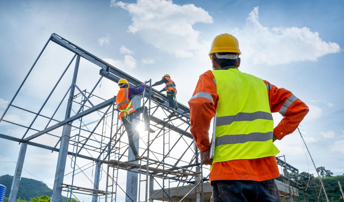 Công nhân xây dựng đang làm việc trên công trường với các dầm thép dưới bầu trời xanh.
