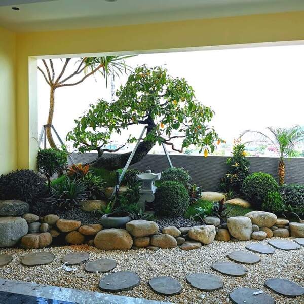 Khu vườn Nhật Bản nhỏ trong nhà với cây bonsai, đá cuội và đèn đá trang trí.