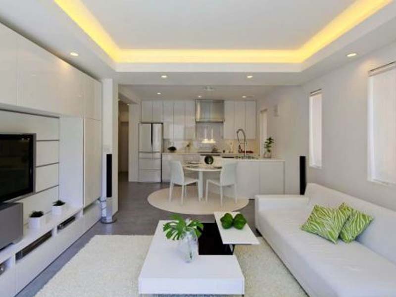 Phòng khách hiện đại với nội thất trắng, sofa thẳng, bàn trà và cây xanh tạo không gian thoáng đãng.