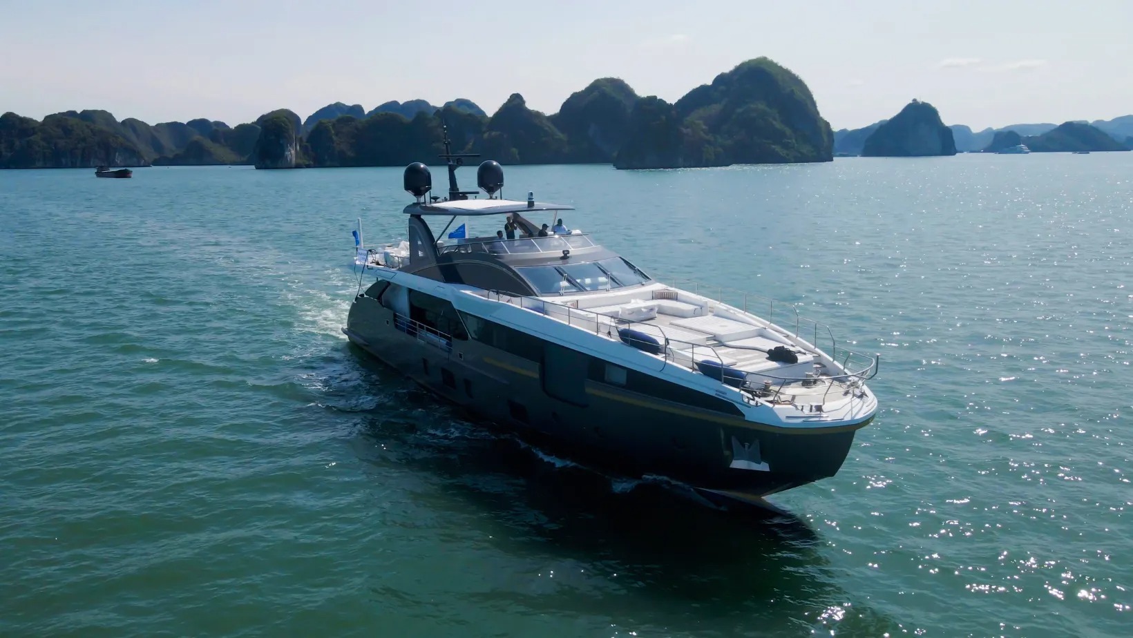 Du thuyền hiện đại trên vịnh Hạ Long ngày nắng, nền trời trong xanh và cảnh quan núi non hùng vĩ.