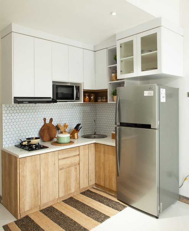 Nhà bếp hiện đại với tủ lạnh inox, kệ gỗ, lò vi sóng và trang trí gạch tổ ong.