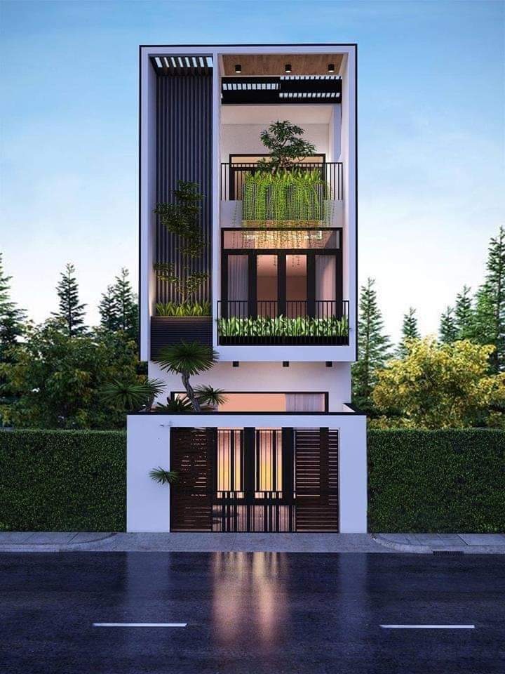 Nhà phố hiện đại ba tầng với kiến trúc sáng tạo và cây xanh trang trí ban công, nổi bật trên nền trời xanh.