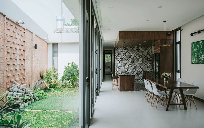 Nhà bếp hiện đại với bàn ăn gỗ nhìn ra sân vườn qua cửa kính lớn, ánh sáng tự nhiên tràn ngập.