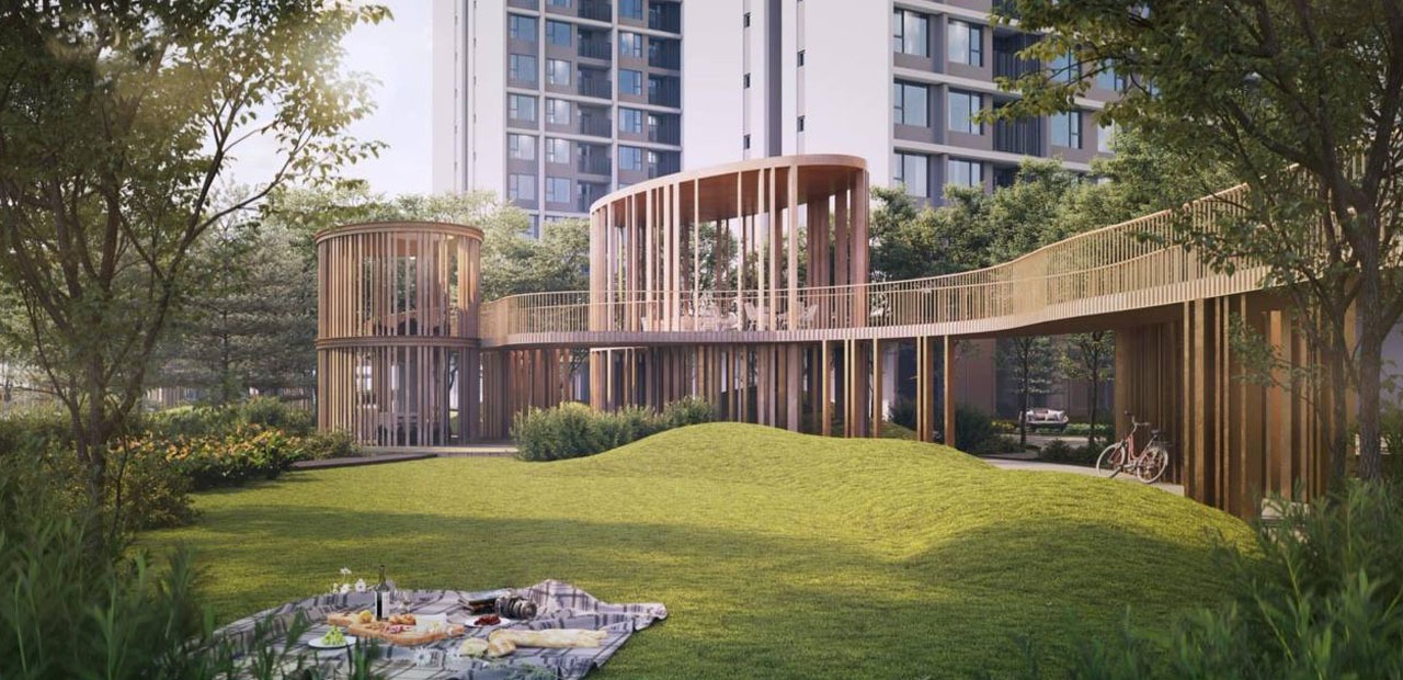 Khu vườn xanh mướt với lối đi bằng gỗ hiện đại gần tòa nhà, có điểm picnic trên thảm cỏ.