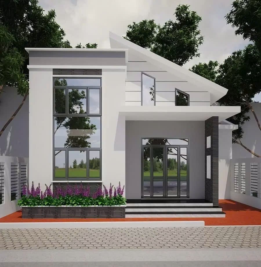 Nhà hiện đại 2 tầng với cửa kính lớn, sân lát gạch, vườn cây xanh mát phía trước.