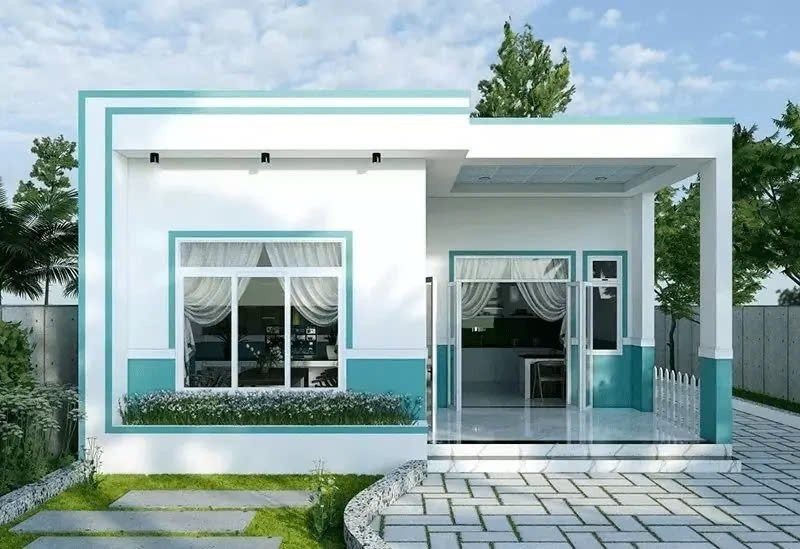 Nhà cấp 4 hiện đại với tông màu trắng và xanh, cửa kính lớn, sân lát gạch, xung quanh cây xanh.