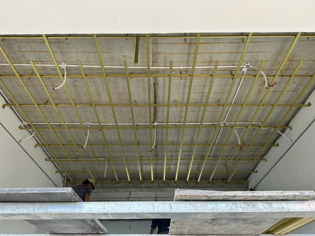 Khung trần thi công với hệ thống dây điện và đèn LED chưa hoàn thiện trong tòa nhà.