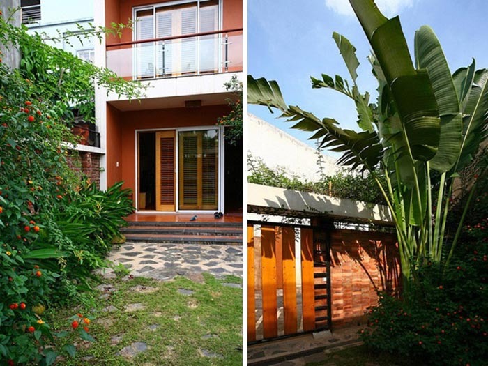 Nhà có sân vườn xanh và cổng gạch đỏ, cây cảnh lớn và đường lát đá tạo không gian thoải mái.